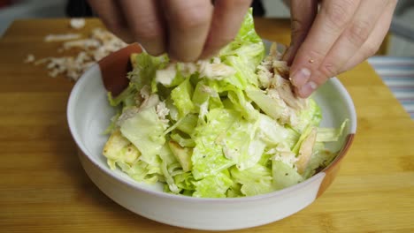 Adding-Chicken-meat-to-a-plate-of-Caesar-salad