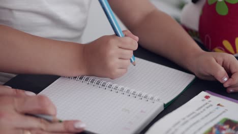 Close-up-of-young-student-girl-hands-writing-in-notebook-studying-at-home