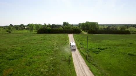 aerial large horse trailer pulled by pickup truck travels down rural dirt road turns unto another dirt road off for an adventure