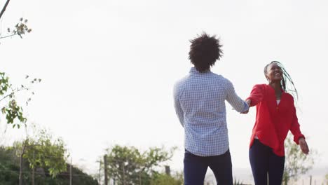 Fröhliches-Afroamerikanisches-Paar,-Das-An-Einem-Sonnigen-Tag-Zusammen-Geht-Und-Händchen-Hält,-Zeitlupe