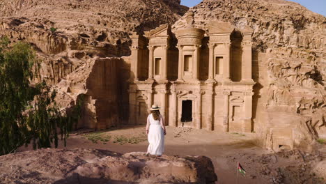 tourist woman in front of the ad deir monastery in petra, jordan at sunset - aerial drone shot