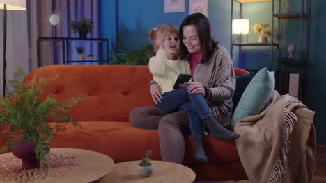 madre y niña niña hija mirando en el teléfono inteligente regocijándose ganar, recibiendo mensaje con buenas noticias