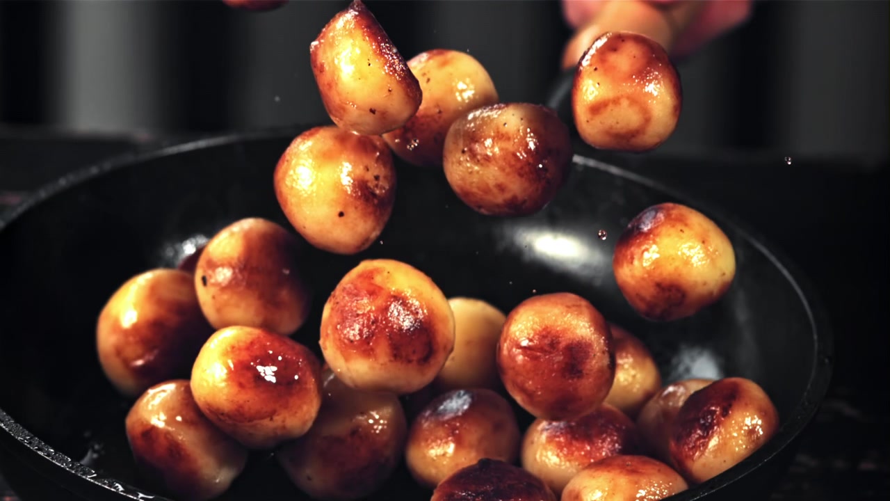 Patate arrosto dorate che saltano in una padella calda al rallentatore