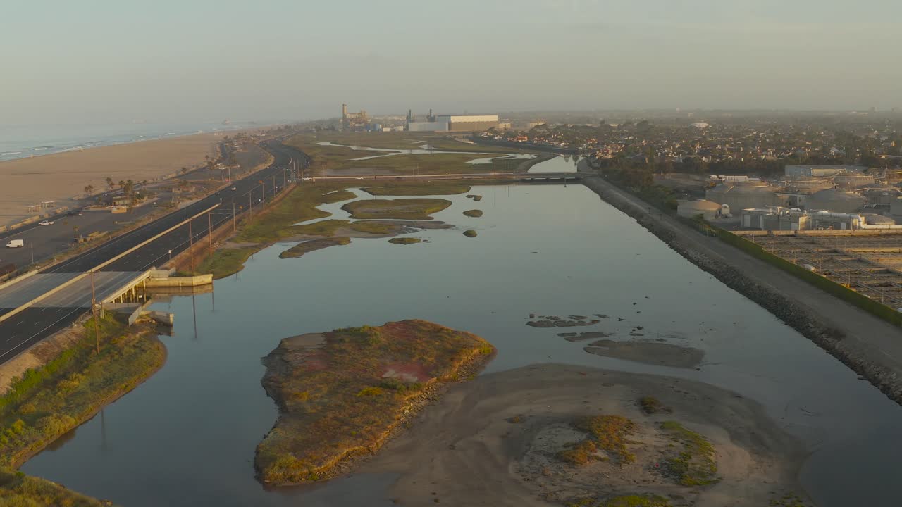 un dron comienza a nivel del suelo y se eleva para revelar casas frente al mar al amanecer