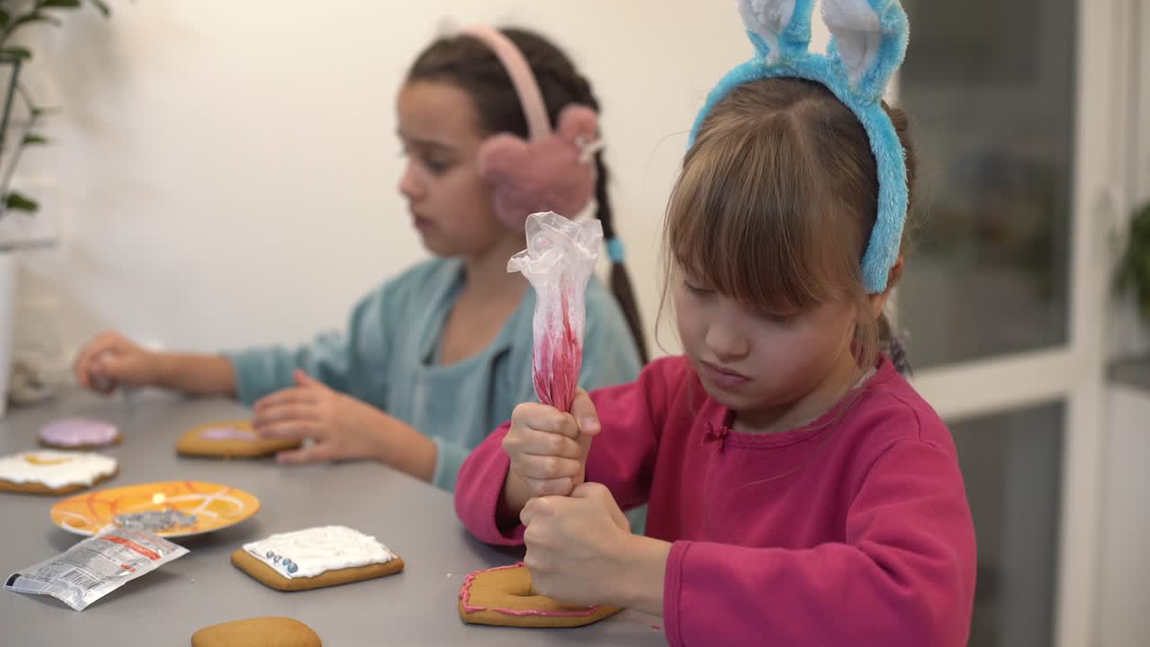 dos hermanas pequeñas decorando galletas caseras en la cocina en casa.
