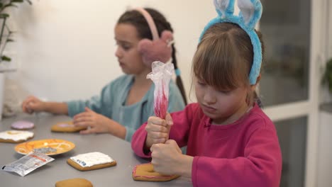 Zwei-Kleine-Schwestern-Dekorieren-Hausgemachte-Kekse-In-Der-Heimischen-Küche.