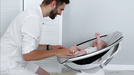 el padre juega con el bebé que yace en la cuna moderna. el concepto de estilo moderno.