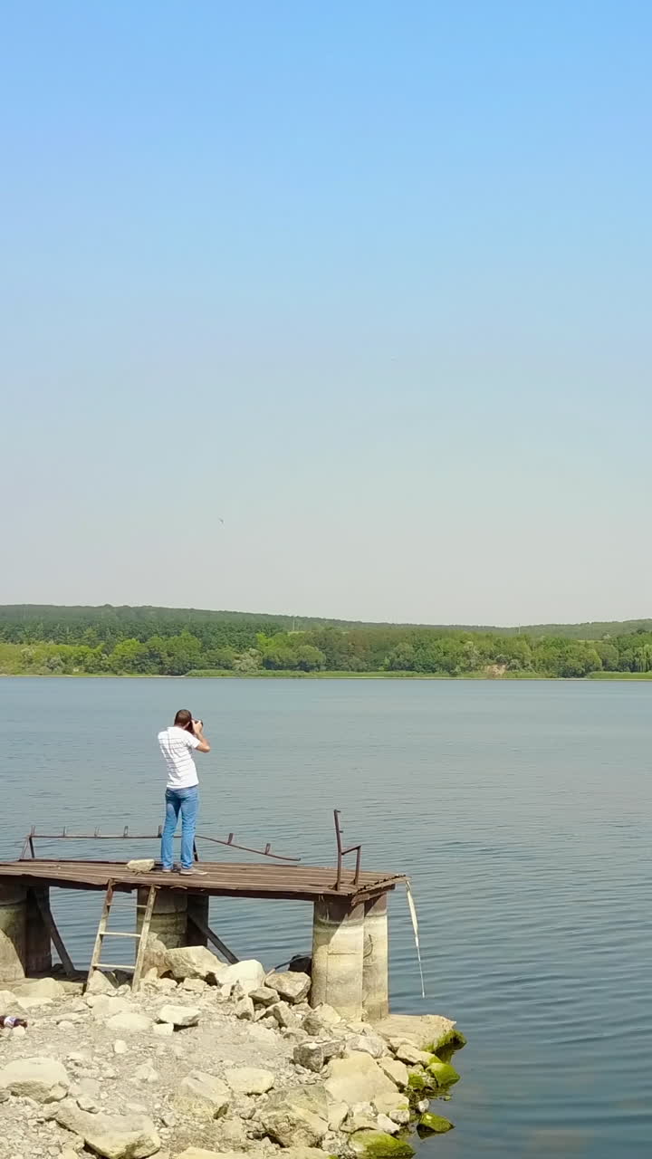 Man Taking Photos Near Pond. Photographer photographing landscape near river