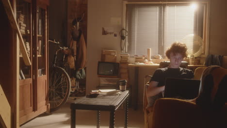 young man relaxing on couch and using laptop in cozy living room