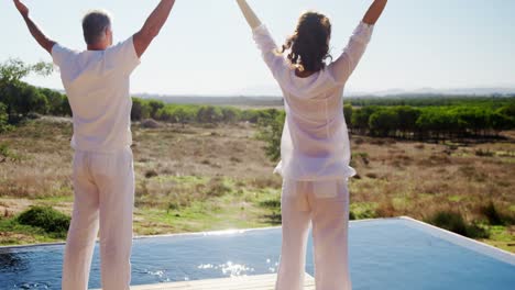 Senior-couple-with-arms-outstretched-standing-near-poolside-4k