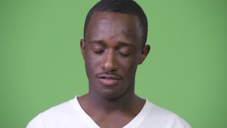 young african man nodding no against green background