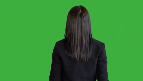 mujer de negocios de buen aspecto en ropa de negocios de pie frente a un fondo de pantalla verde. mujeres de raza mixta promoviendo, para la llave de croma