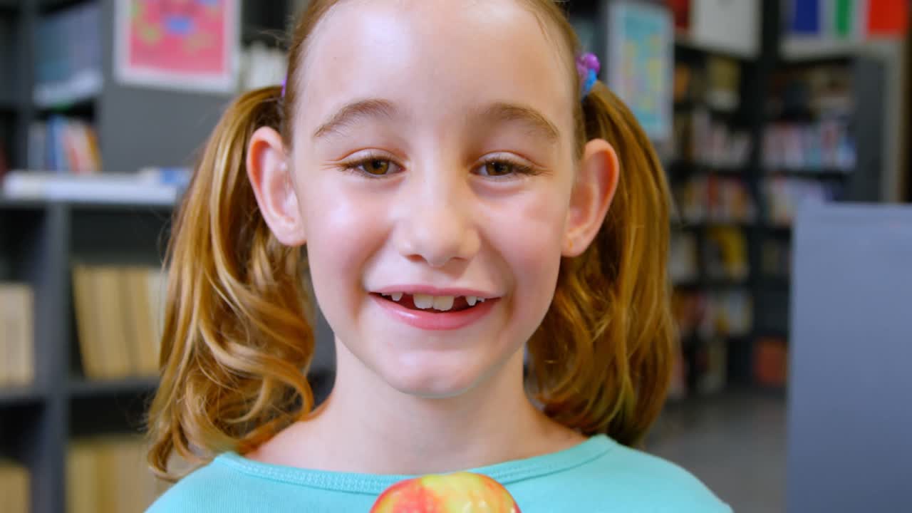 Front view of happy Caucasian schoolgirl standing in library at school 4k