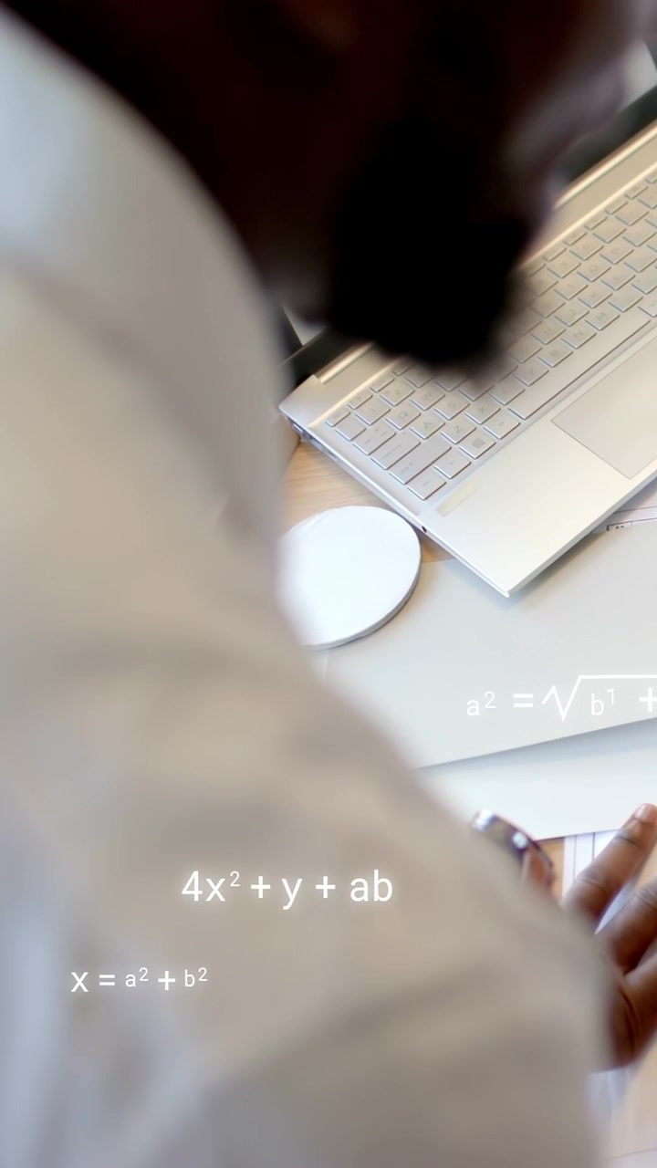 Vertical video: Man leaning at desk using laptop and docs watching equations rising for education