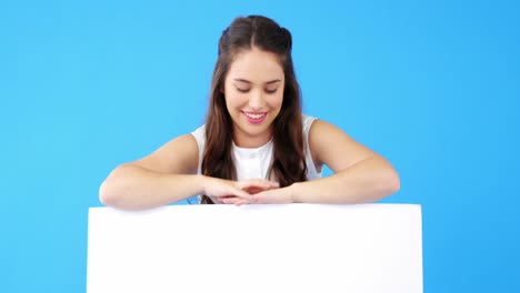 Beautiful-woman-holding-blank-placard-on-blue-background