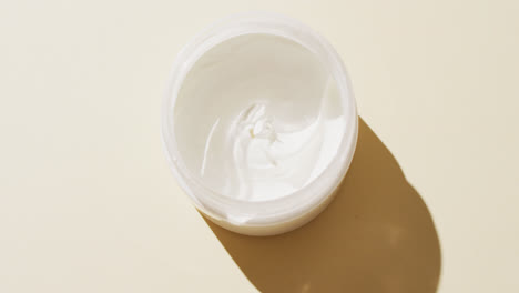 primer plano de crema blanca sobre fondo beige con espacio para copiar