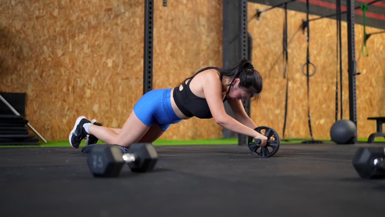 Woman doing ab roller workout in the gym