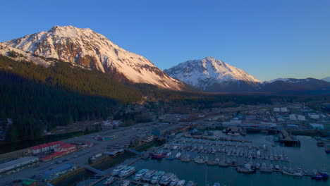 Malerische-Drohnenansicht,-Die-Bei-Sonnenaufgang-In-Seward,-Alaska,-Vom-Bootshafen-Und-Den-Bergen-Von-Seward-Wegfliegt