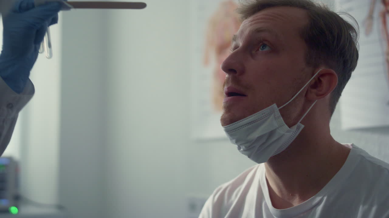 paciente boca abierta dando pruebas en la clínica de cerca. médico tomando muestra de saliva