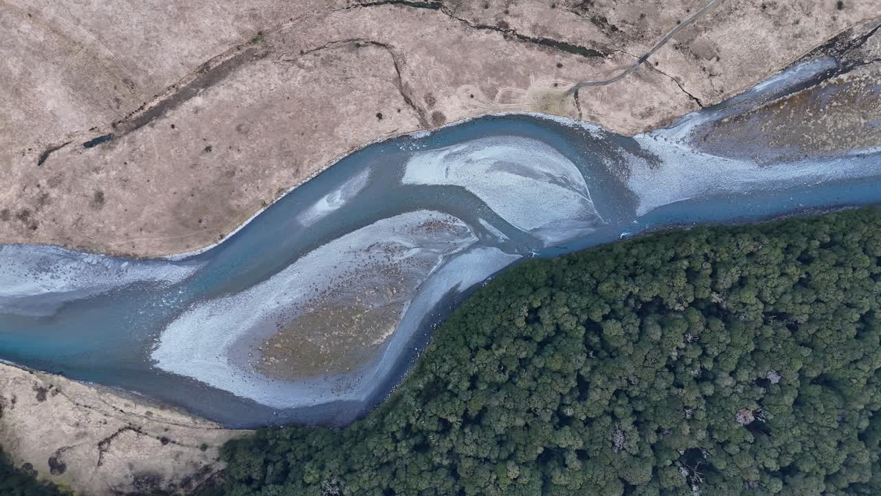 Aerial top down of river and forest trees at Mount Aspiring area in New Zealand. Sunny day in fall. Pattern of river and drought
