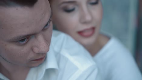 young beautiful couple sitting in the morning on the bed they look at each other thoughtfully close-up