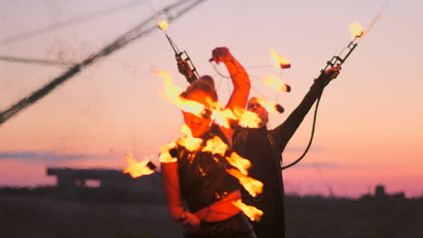 a group of professional circus performers with fire shows dance shows in slow motion using flame-throwers and rotating the torches burning objects