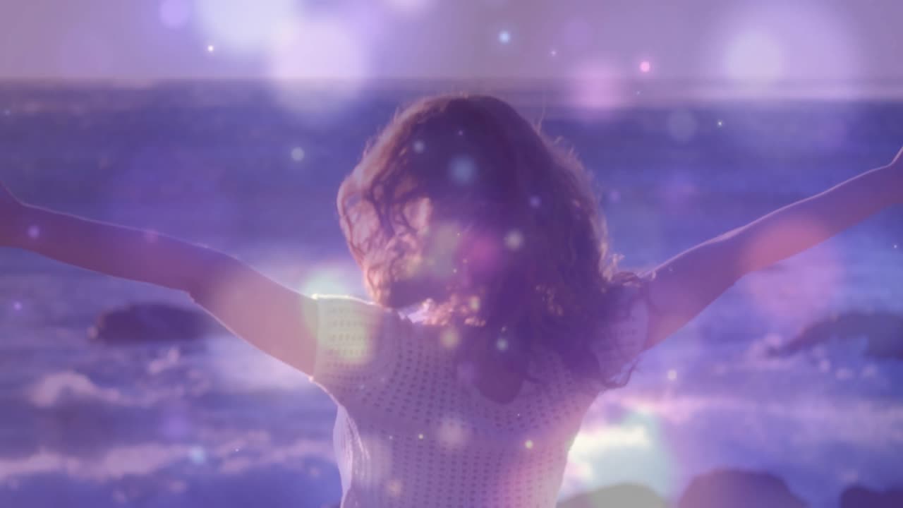 Luz solar creando destellos de lente que iluminan a mujer abriendo los brazos para el bienestar en la playa con efecto bokeh