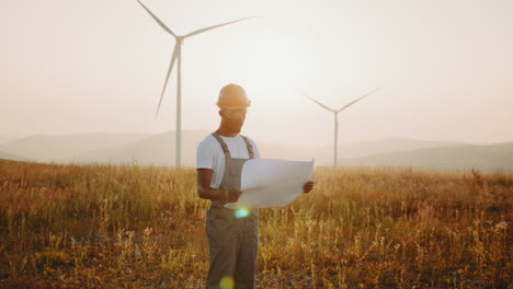 engineer reviewing wind farm plans at sunset