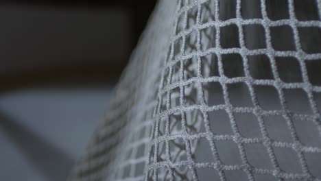 extreme close up shot of ice hockey net, puck is kicked into it and bounces off