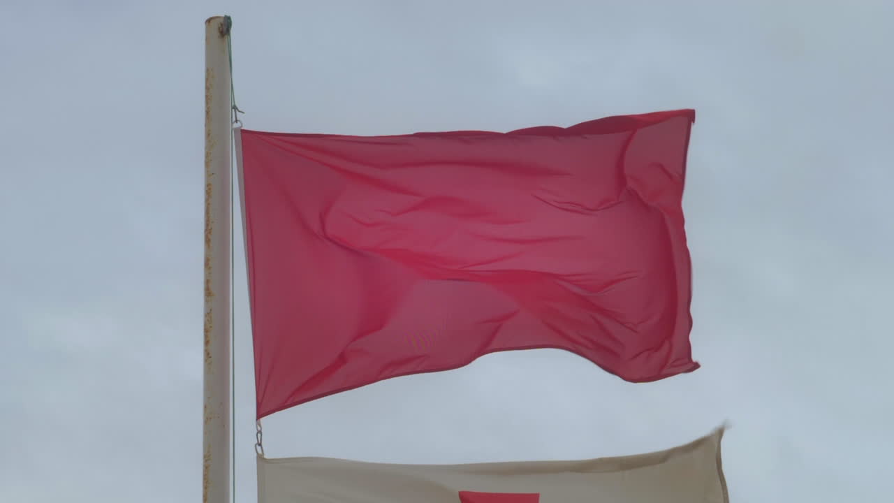 bandera roja ondeando en un día ventoso y tormentoso en la playa
