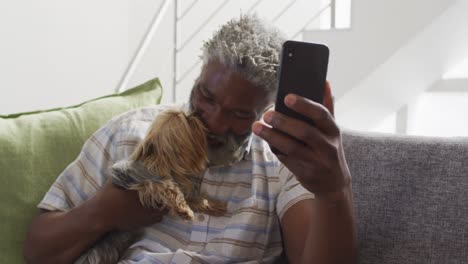 Älterer-Mann-Hält-Seinen-Hund-Und-Führt-Zu-Hause-Einen-Video-Chat-Auf-Dem-Smartphone