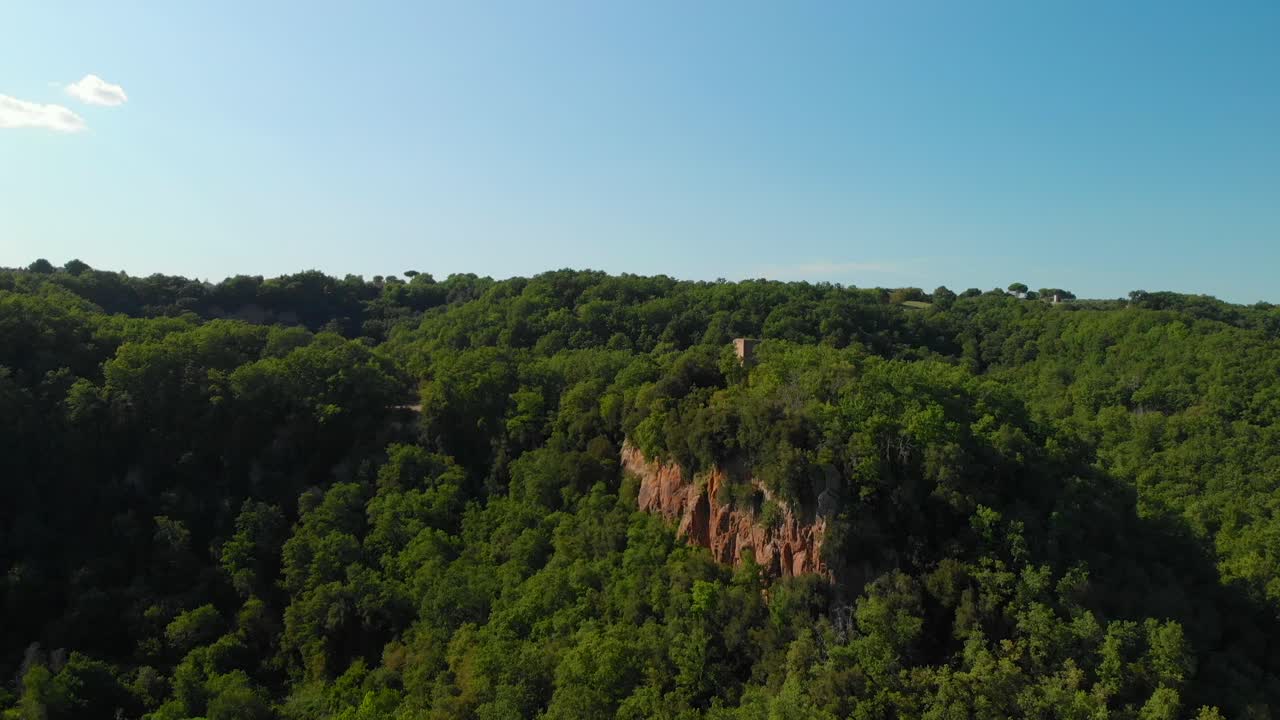 drone elevándose sobre un valle verde, con bosques de verano, algunas montañas rocosas y un cielo azul, italia, antena 4k