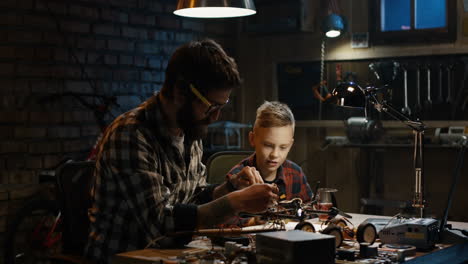 father and son building a robot toy car in a garage