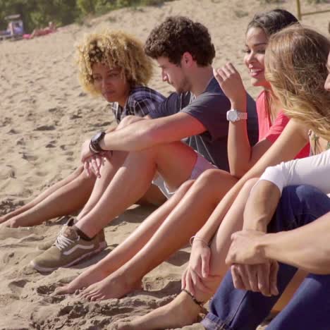 Gruppe-Gemischtrassiger-Menschen,-Die-An-Einem-Strand-Sitzen