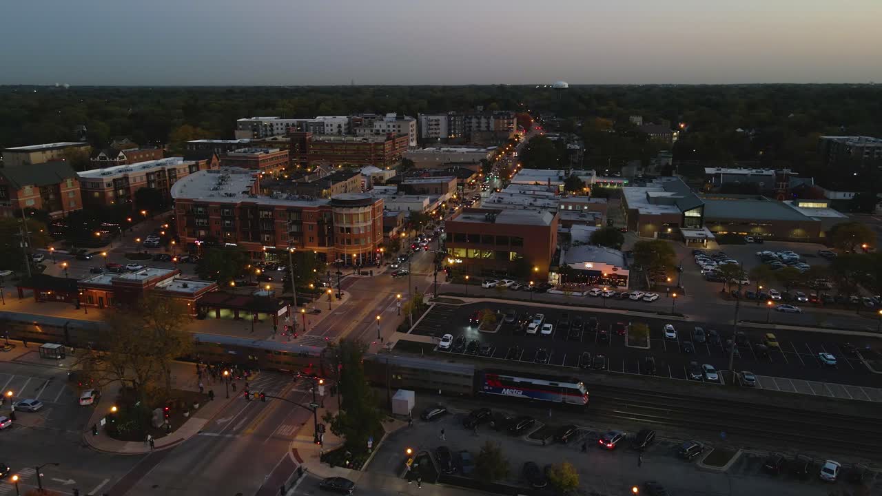Metra commuter train crossing Downers Grove Illinois train station at night with illuminated streets. Crane Down Right Night S
