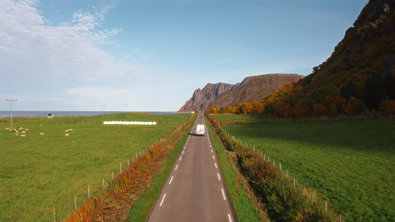 Scenic road leading through vibrant nature with mountain views and an RV on the path