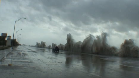 enormes olas golpean un malecón en galveston, texas, durante un huracán o una tormenta masiva mientras un automóvil pasa