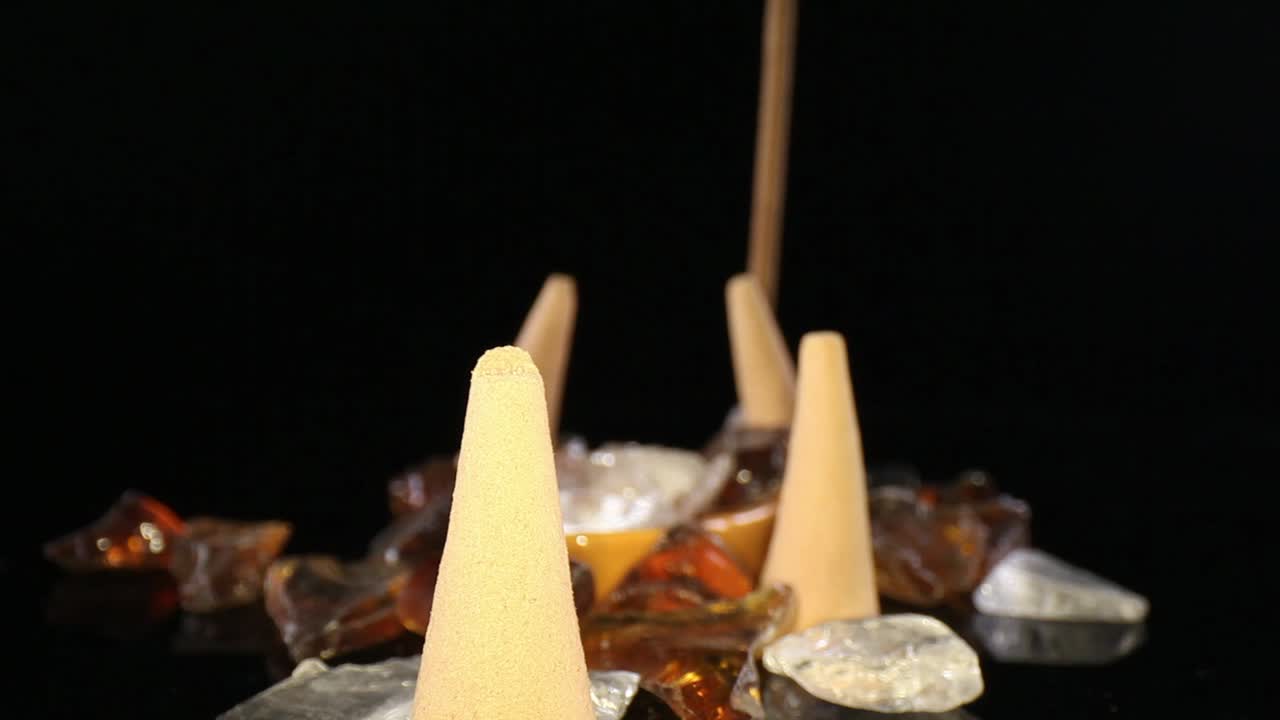 empujando hacia varios conos de incienso apagados en un jardín de rocas decorativas, hacia un palo con poco humo