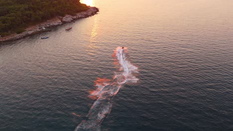 speedboat cuts through calm ocean water during sunset near ksamil, albania, creating ripples