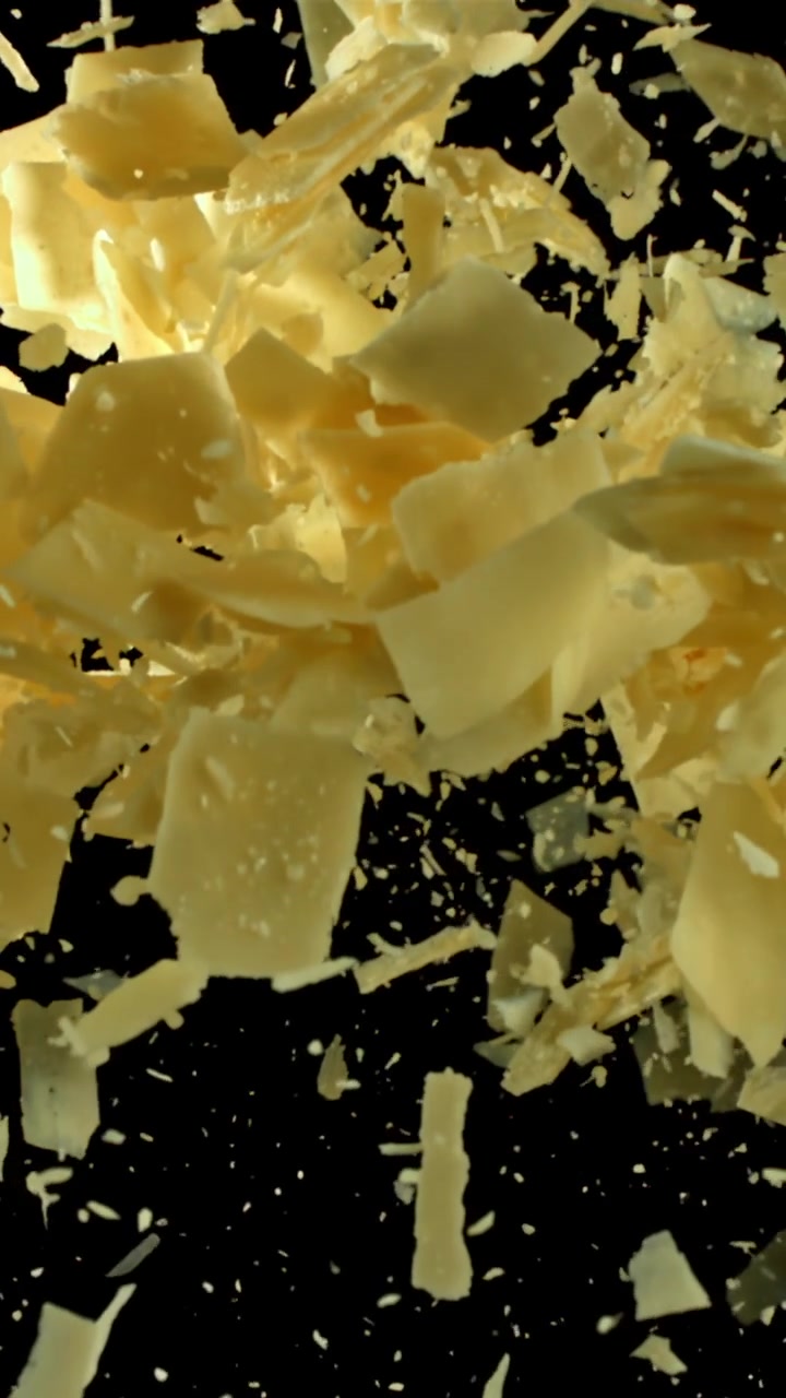 Parmesan Cheese Flakes Falling in Slow Motion on Black Background