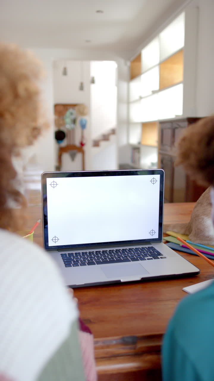 Vertical video of biracial mother and son using laptop with copy space, slow motion