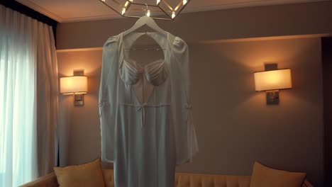 a smooth shot of a bridal wedding dress, hanging in a decorate room