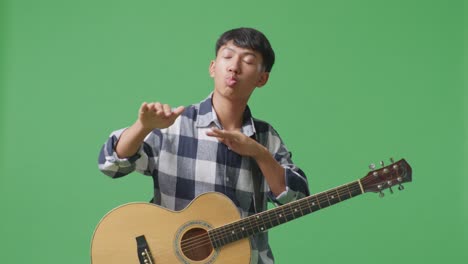 asian teenager with guitar dance on green screen background