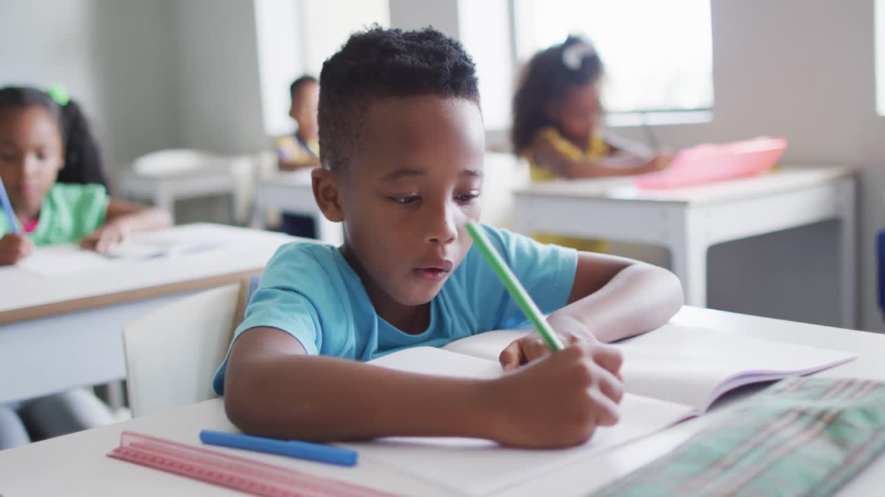 Video of focused african american boy doing lessons in classroom