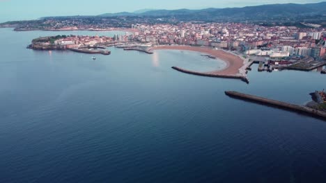 panoramic aerial drone footage of gijon cityscape at sunset, beach port commercial touristic harbor, north of spain