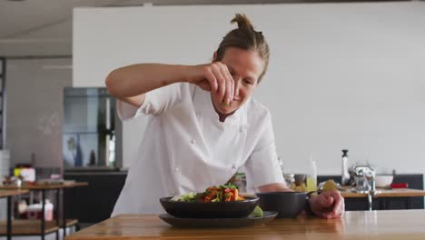 caucasian female chef preparing a dish and smiling in a kitchen