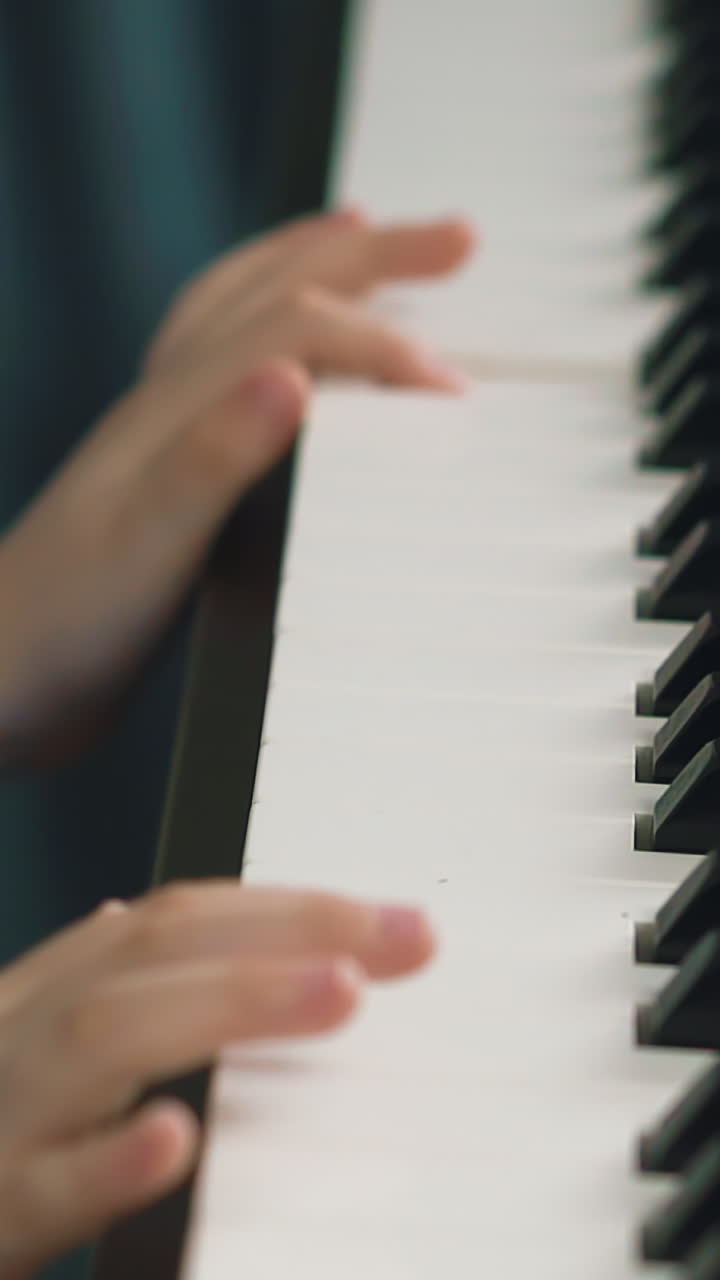 CU shot, slow motion: little child plays modern music synthesizer pressing white and back keys in light room extreme close view