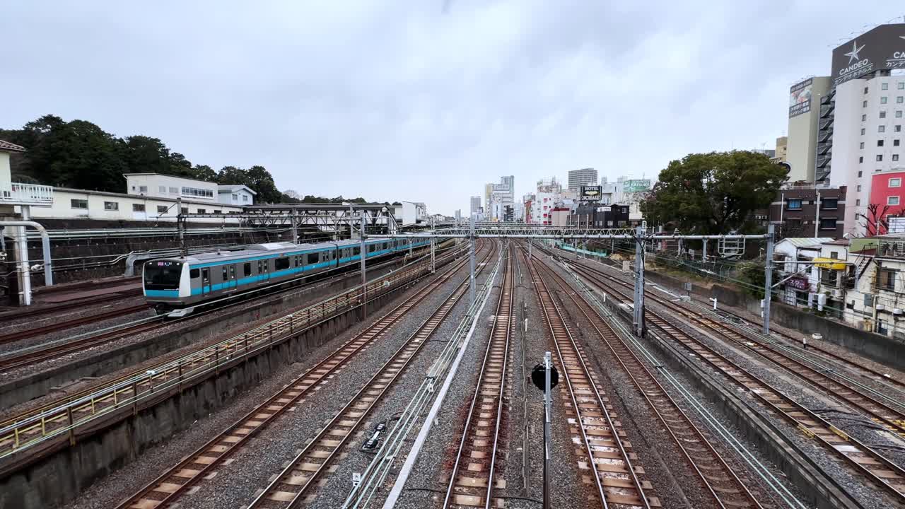 Aerial shot of a train station in Japan with multiple tracks and a passing train