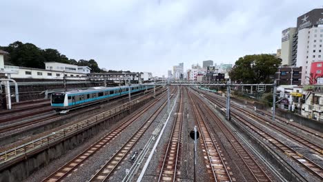 aerial shot of a train station in japan with multiple tracks and a passing train