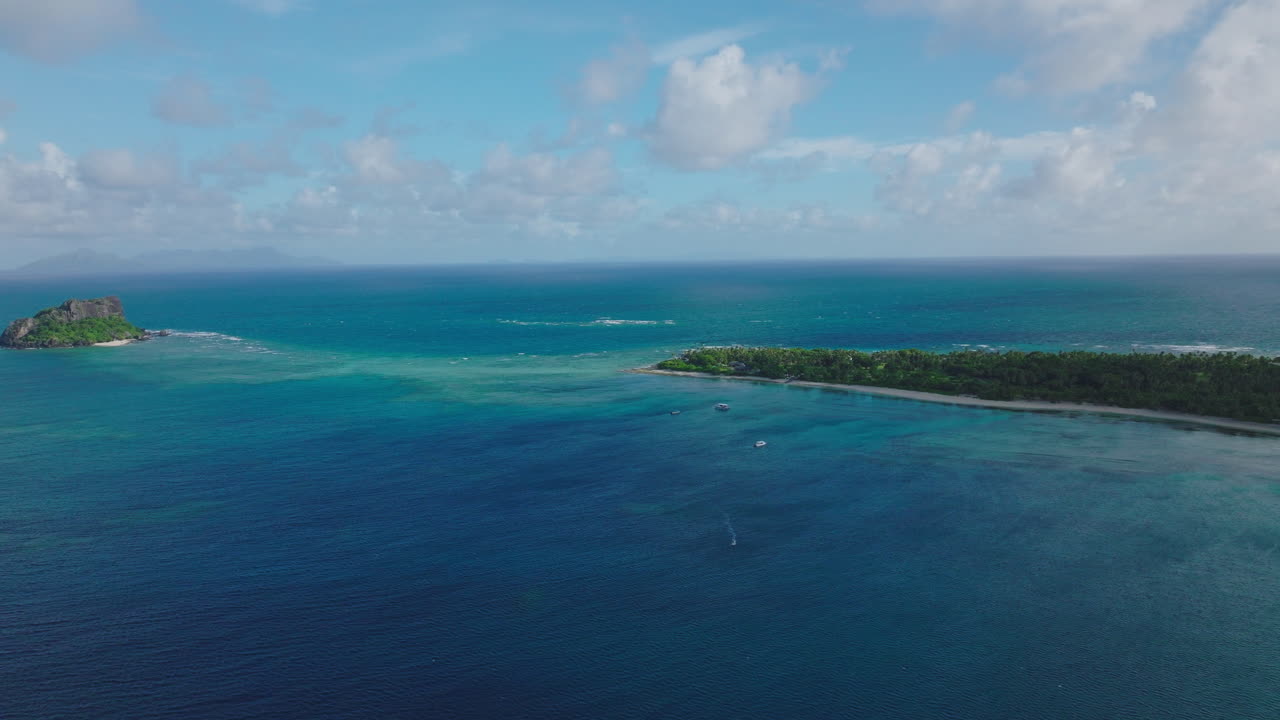 Sweeping aerial of shallow reef and deep water drop off in pristine tropical ocean